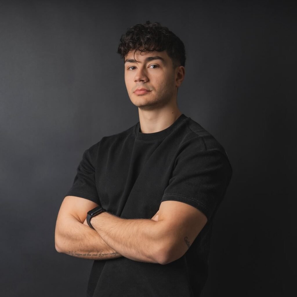 Pietro in posa con le braccia incrociate in piedi su uno sfondo nero